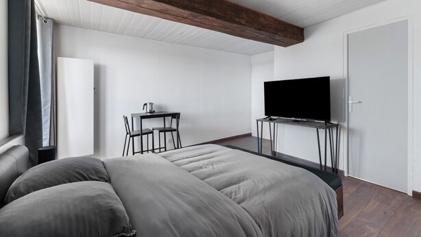 A modern bedroom with a large bed, a desk, a television, and a door. - La Bohème Room 3 with Wi-Fi (Frossay)