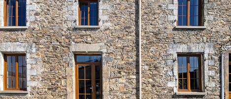 A stone building with multiple windows and a bench outside.