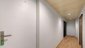 A hallway with a wooden floor, white walls, and a door with a key lock. - La Bohème Room 3 with Wi-Fi (Frossay)