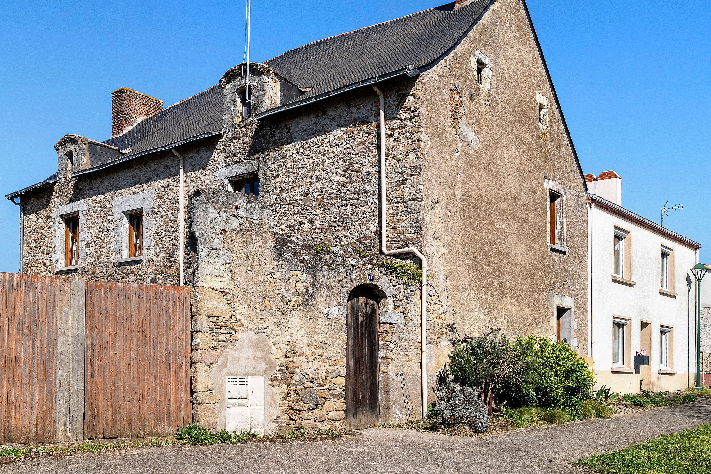 A stone building with a wooden door, a small window, and a chimney.