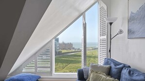 Ein Zimmer mit einem großen Fenster, einem blauen Sofa und einer Lampe.
