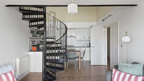 Ein modernes Interieur mit einer Wendeltreppe, einer Küche mit weißen Schränken und einem Essbereich.