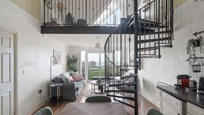 Ein modernes Loft mit zentraler Treppe, einem Essbereich und einem Wohnzimmer mit Stadtblick.