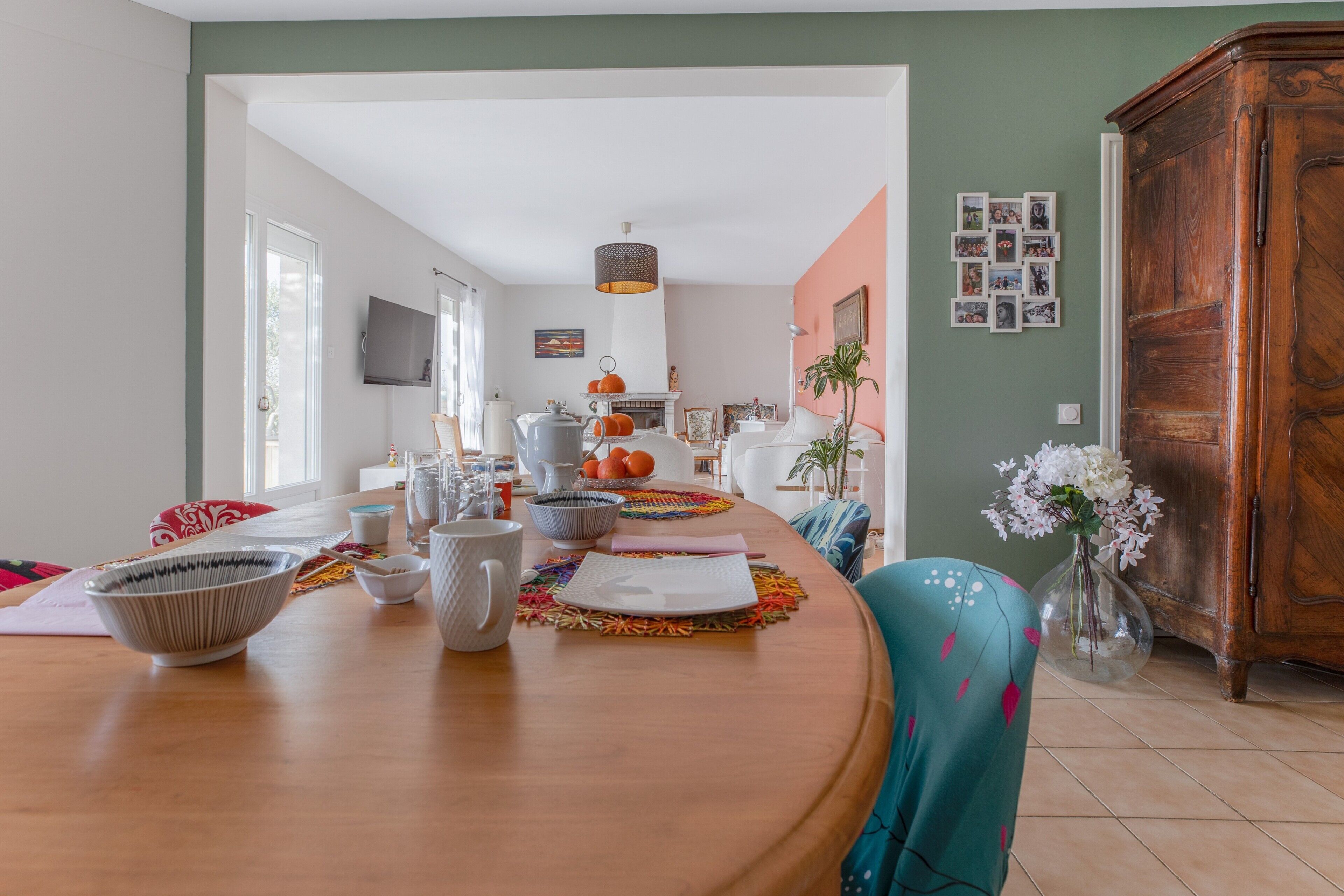 Un coin repas avec une table en bois, des chaises et un vase de fleurs.