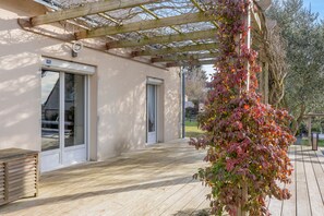 A covered outdoor area with a wooden deck, a pergola, and a wall-mounted air conditioning unit. - Guest Room “La Gâtine” with Pool, Terrace & Wi-Fi in Rochecorbon (Rochecorbon)