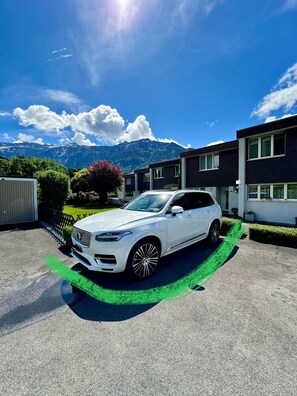 Een witte SUV op een oprit, met bergen op de achtergrond.