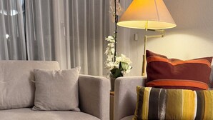 Un salon avec une table basse en verre, deux canapés, une lampe et une plante en pot.