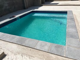 Una piscina rectangular con borde de baldosas y contorno de piedra.
