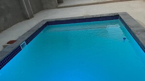 En rektangulär swimmingpool med blå kakelplattor längs kanterna och en klar, blå vattenyta.