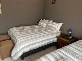 A bedroom with a bed, a nightstand, a lamp, and a small table.