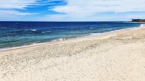 Una playa con vista despejada al océano y un edificio distante.