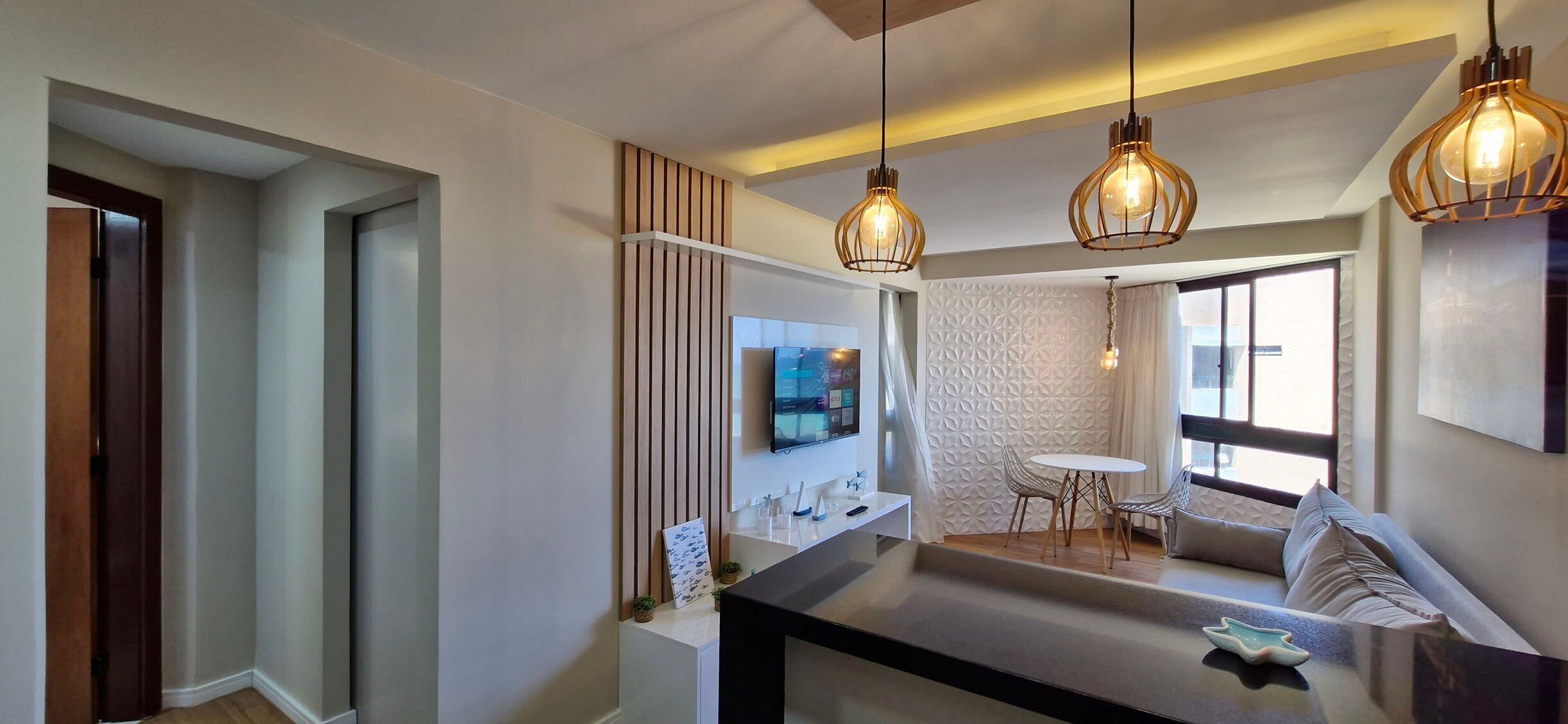 A modern kitchen with a central island, pendant lighting, and a dining area with a table and chairs.