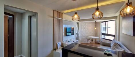 A modern kitchen with a central island, pendant lighting, and a dining area with a table and chairs.