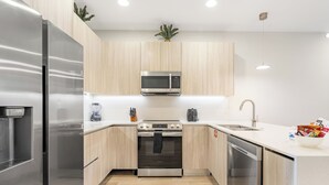 Una cucina moderna con elettrodomestici in acciaio inossidabile, mobili in legno e un piano di lavoro bianco.