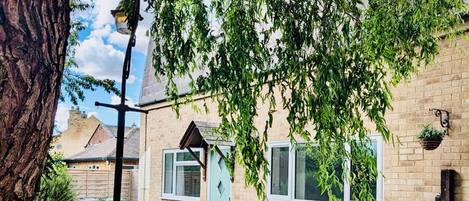 Une rue résidentielle avec une maison en briques, un arbre et une plante suspendue.