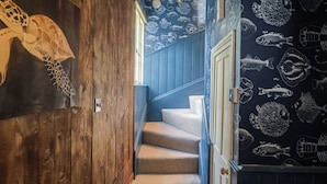 A wooden staircase with a blue wall featuring fish patterns. - 5B Bridge Street (Lyme Regis)