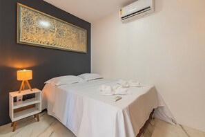 Ein Hotelzimmer mit einem Bett, einer Nachttischlampe, einer Wandklimaanlage und einem großen dekorativen Element über dem Bett.