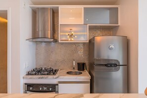 Eine Küche mit Gaskochfeld, Edelstahlkühlschrank und gefliestem Spritzschutz.