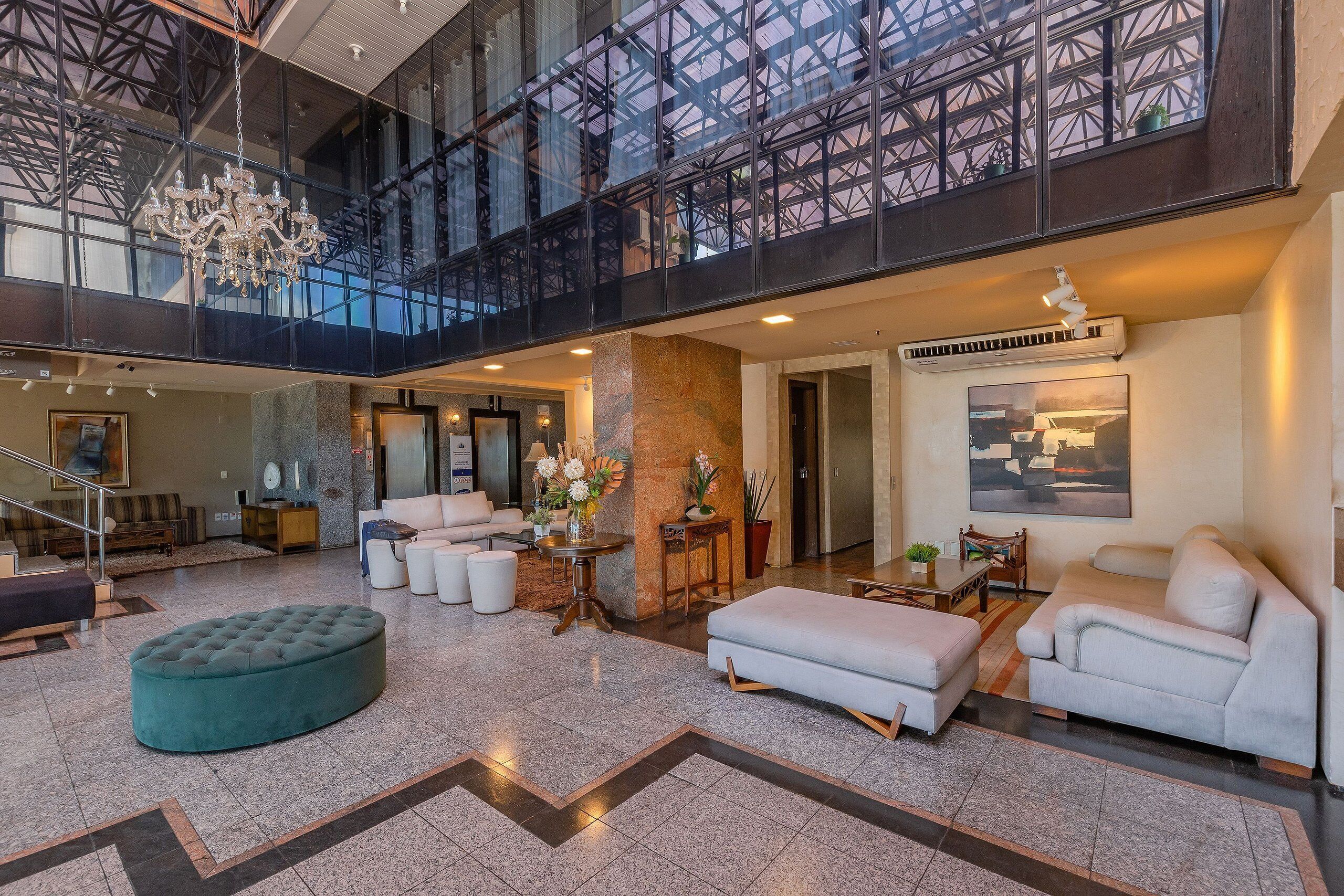 Un vestíbulo amplio con techo alto, un candelabro, una escalera y un gran ventanal con vistas al interior.