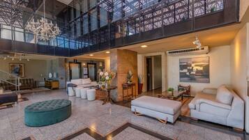 Un vestíbulo amplio con techo alto, un candelabro, una escalera y un gran ventanal con vistas al interior.