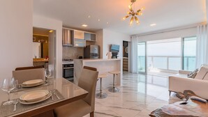 A modern living room with a dining area, a kitchen, and a balcony with a view. - Iracema Residence #1408 - Fortaleza by Carpediem (Fortaleza)