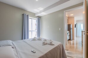 Ein Hotelzimmer mit Bett, Fernbedienung und Blick auf den Flur.