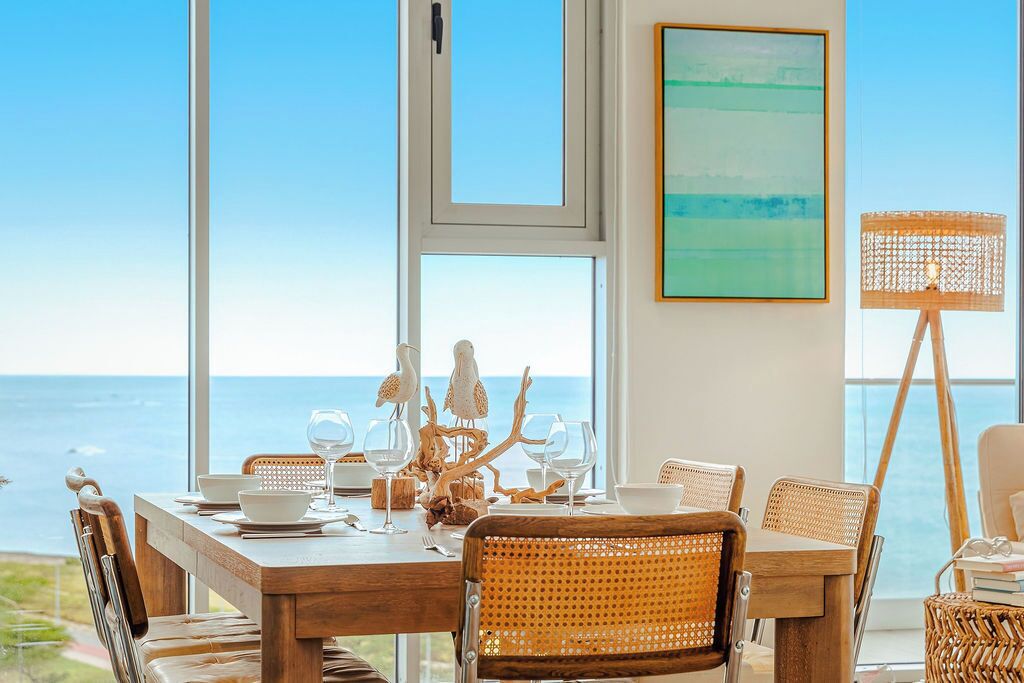 Una mesa de comedor dispuesta con platos blancos, vasos y un centro de mesa decorativo.