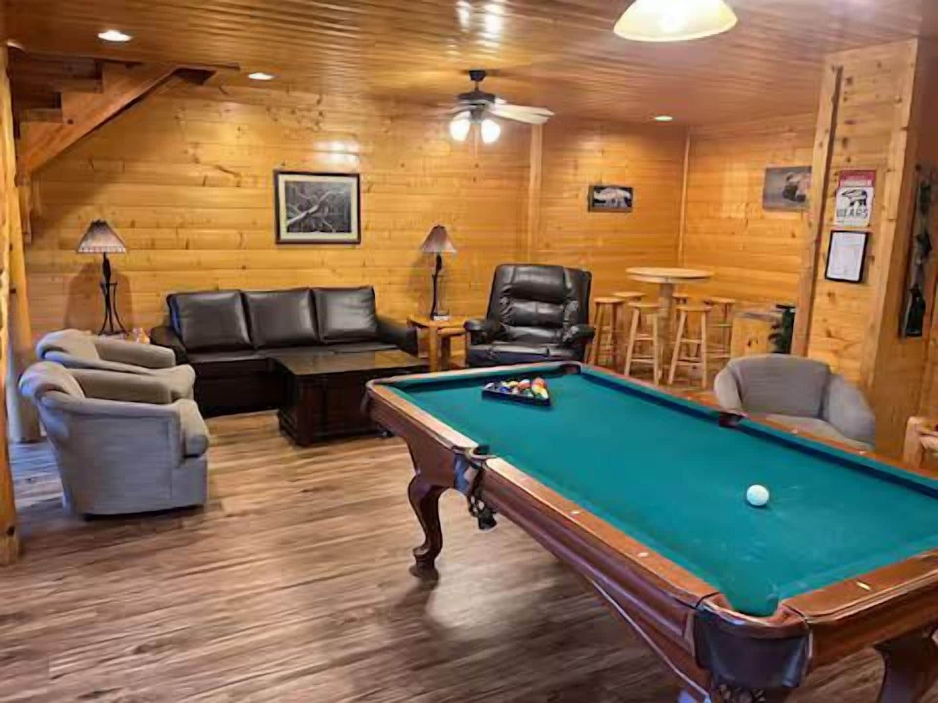 A cozy room with a pool table, leather sofa, and a dining area.