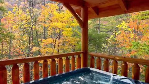 Een hottub op een houten terras, met uitzicht op herfstkleuren.
