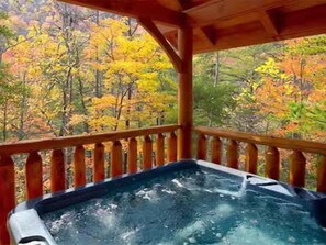 Un bain à remous sur une terrasse en bois, avec vue sur le feuillage automnal.