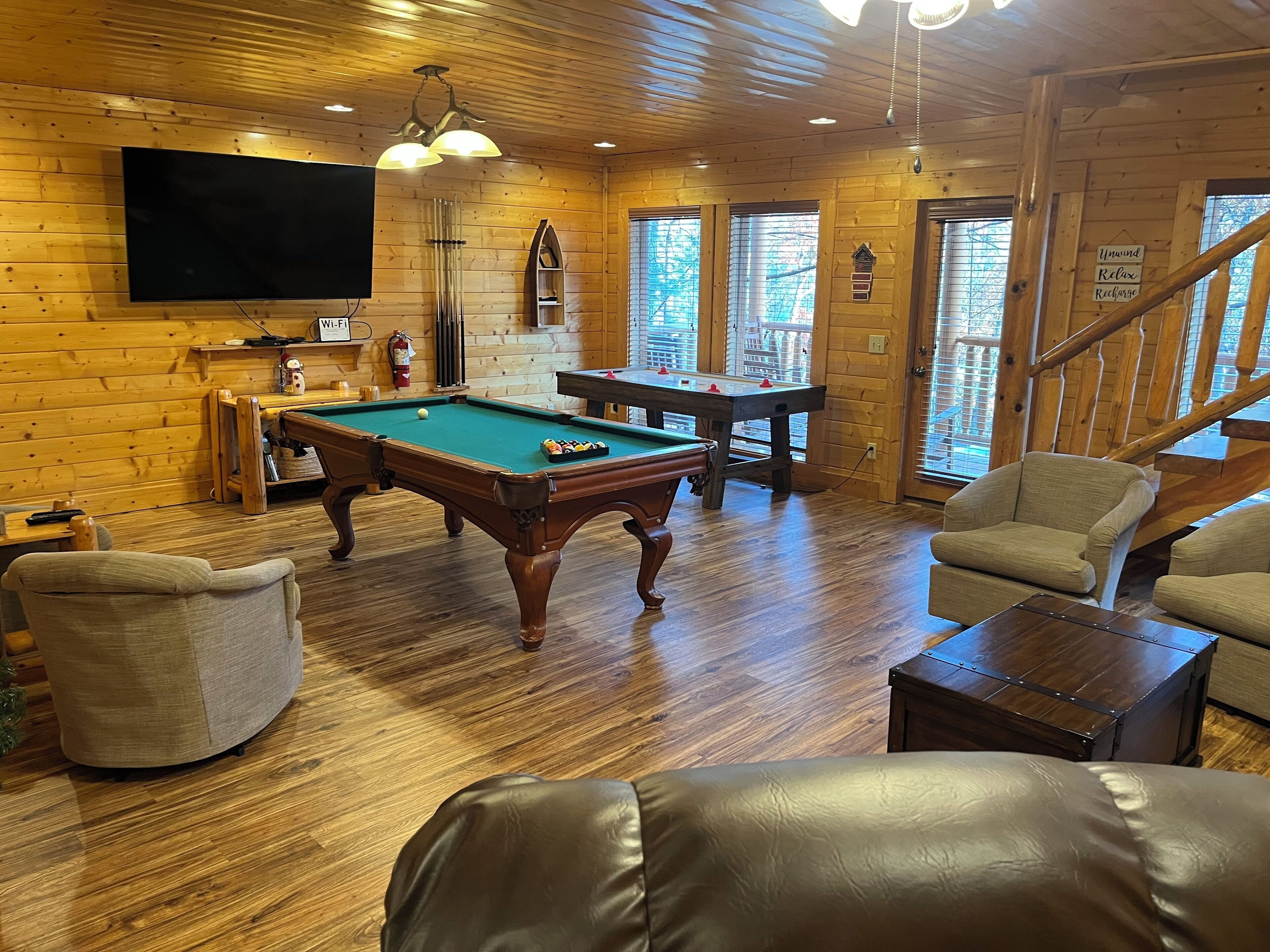 A cozy indoor setting with wooden walls, a pool table, and comfortable seating.
