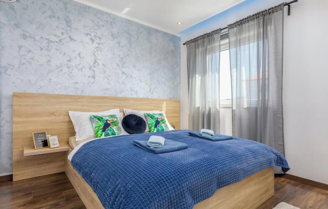 Ein Schlafzimmer mit einem Holzkopfteil, einer blauen Bettdecke und einem Nachttisch mit einem Telefon und einem kleinen Gegenstand.