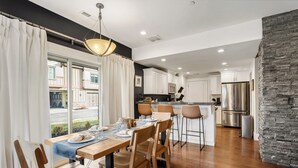 A modern kitchen with white cabinets, a stainless steel refrigerator, and a stone accent wall. - Modern Mountain Home Near Park City & Jordanelle (Kamas)