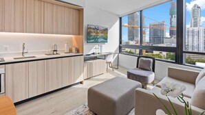 Un apartamento moderno con cocina, comedor y sala de estar con un amplio ventanal con vista a la ciudad.
