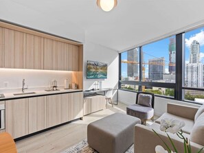 A modern apartment with a kitchen, a dining area, and a living room with a large window offering a city view. - 1-Bed Near FIFA Fan Fest & Kaseya Center (Miami)