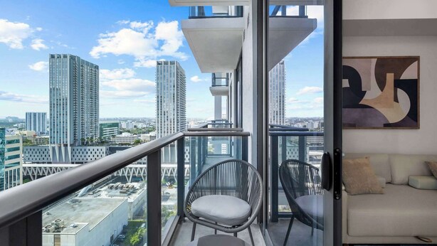 A balcony with a city view, a sofa, and a chair. - 1BR | Rooftop Pool | Walk to Bayfront Park (Miami)