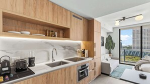 A modern kitchen with wooden cabinets, a marble countertop, and a built-in oven. - Downtown Studio | Rooftop Pool & Skyline Views (Miami)