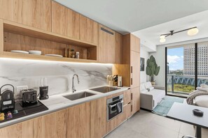 A modern kitchen with wooden cabinets, a marble countertop, and a built-in oven. - Downtown Studio | Rooftop Pool & Skyline Views (Miami)