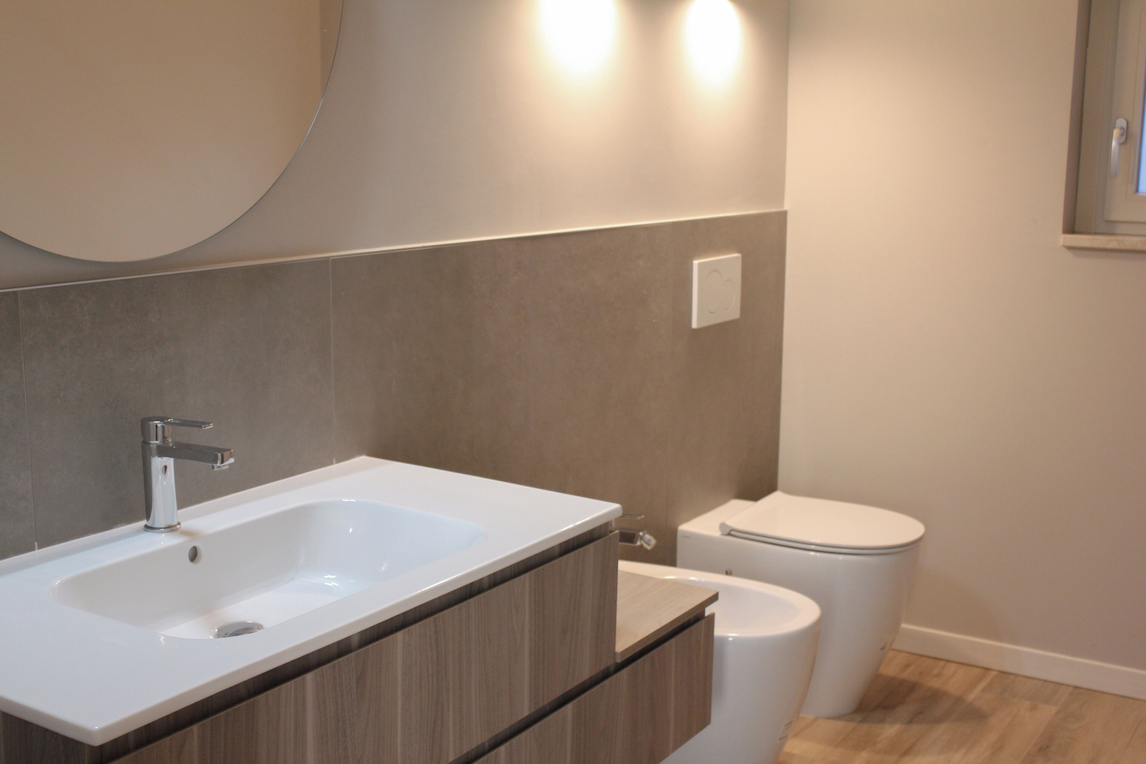 Un baño moderno con lavamanos blanco, tocador de madera y retrete.
