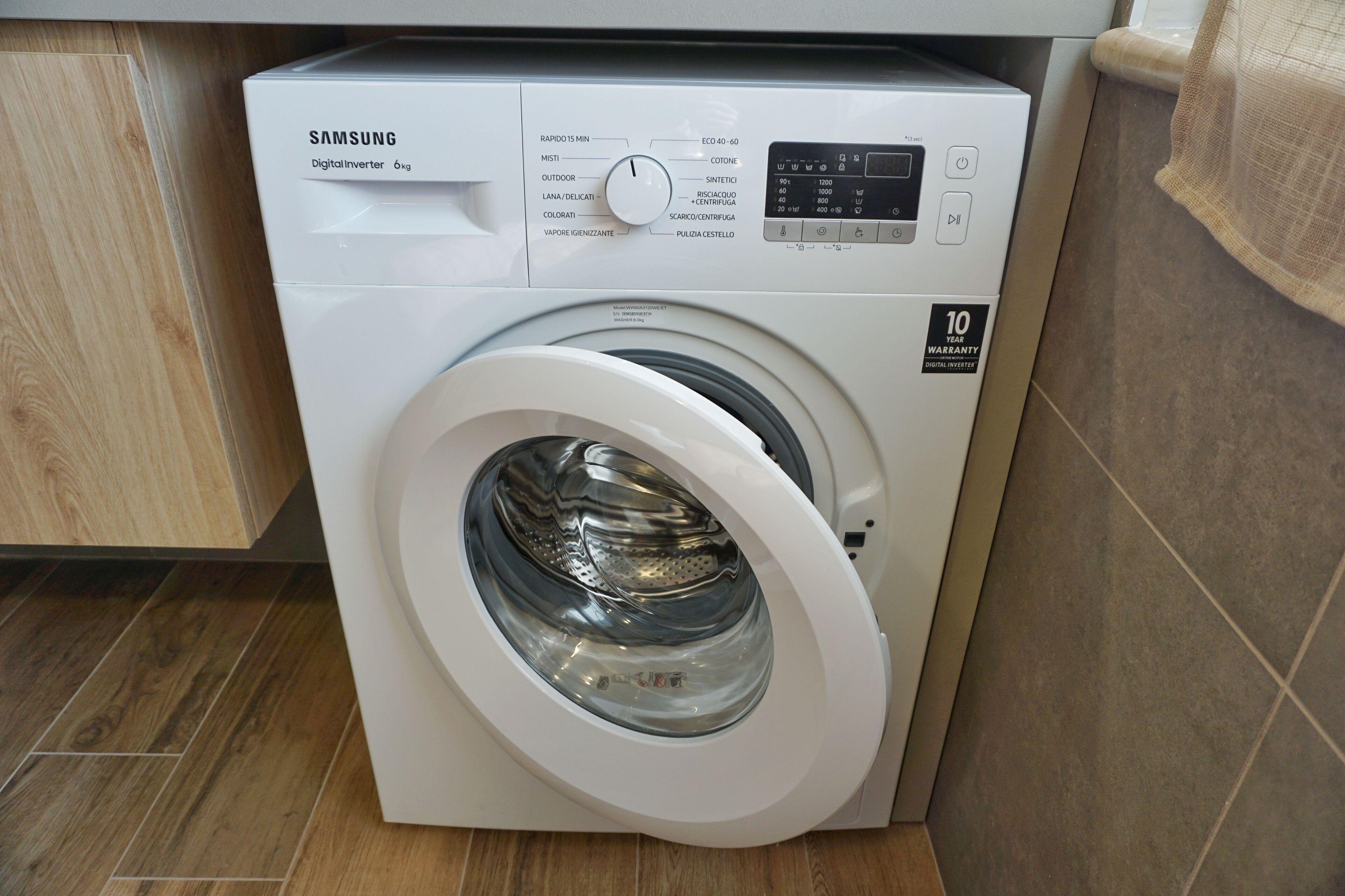 Màquina de rentar amb tecnologia Digital Inverter de Samsung i 10 anys de garantia, situada en una cuina amb sòl de fusta.