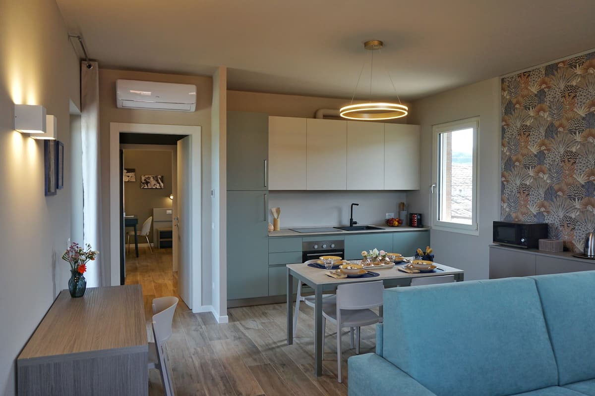 Une cuisine moderne avec un coin repas, comprenant un canapé bleu clair, une table à manger en bois et un îlot de cuisine.