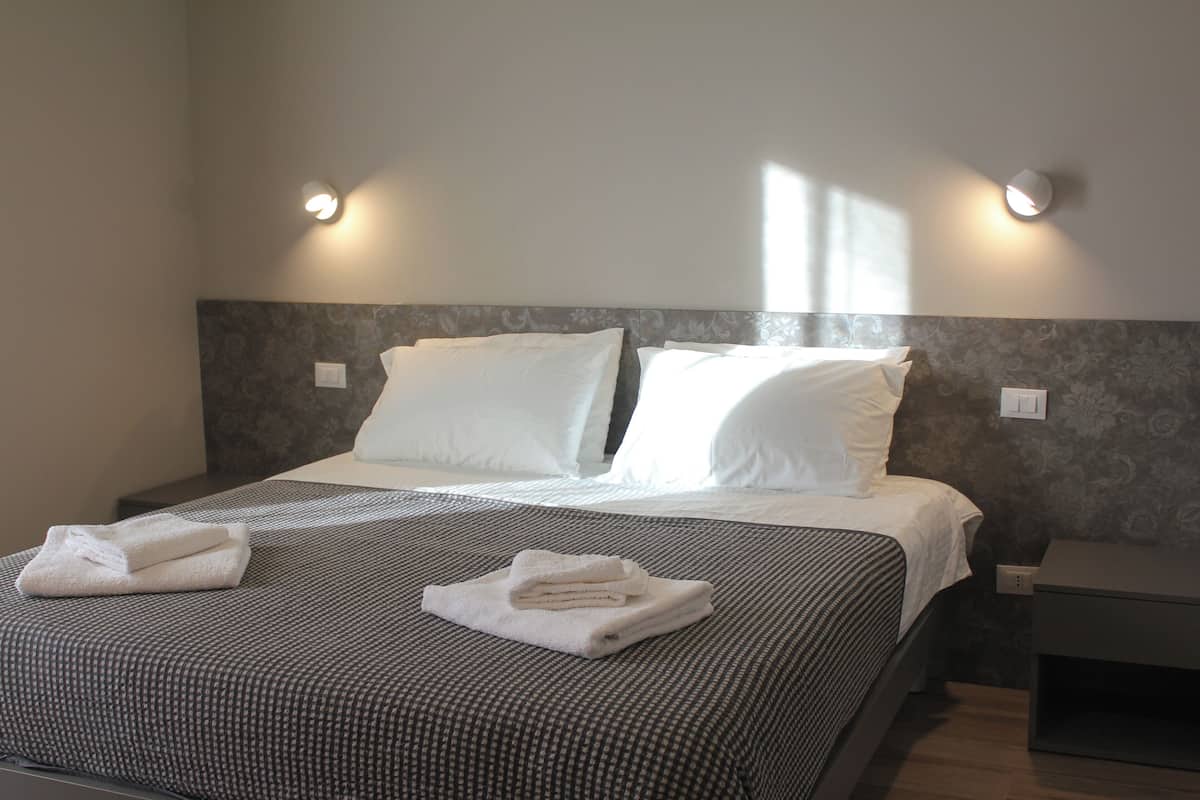 Un lit bien fait, avec une couvre-lit à motifs, deux oreillers et des serviettes pliées posées sur le lit.