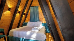 Un dormitorio acogedor en el ático con cama, ventana con cortinas y vigas de madera.