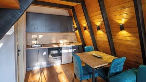 Cocina compacta con electrodomésticos modernos y un comedor con sillas azules.