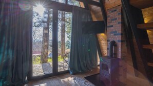 Una cabaña acogedora con un ventanal grande, chimenea y paredes de madera.