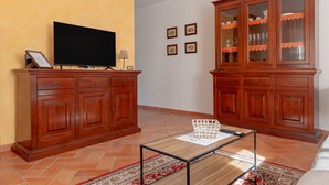 Un salon doté d’un téléviseur à écran plat, de meubles en bois, d’une table basse en verre et d’un tapis à motifs.