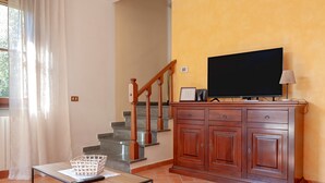 Un salon avec un téléviseur, un meuble en bois et un escalier.