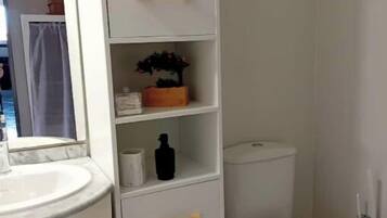 Ein Badezimmer mit einem weißen Waschbecken, einer Toilette und einem Schrank mit Schubladen.