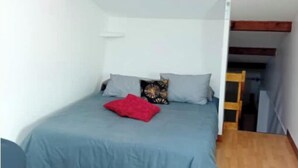 Une chambre à coucher avec un lit, un oreiller rouge et un plancher en bois.