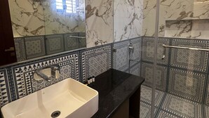 A modern bathroom with a marble wall, a white sink, and patterned tiles. - Ambassador Villa - An Experiential stay (Agra)